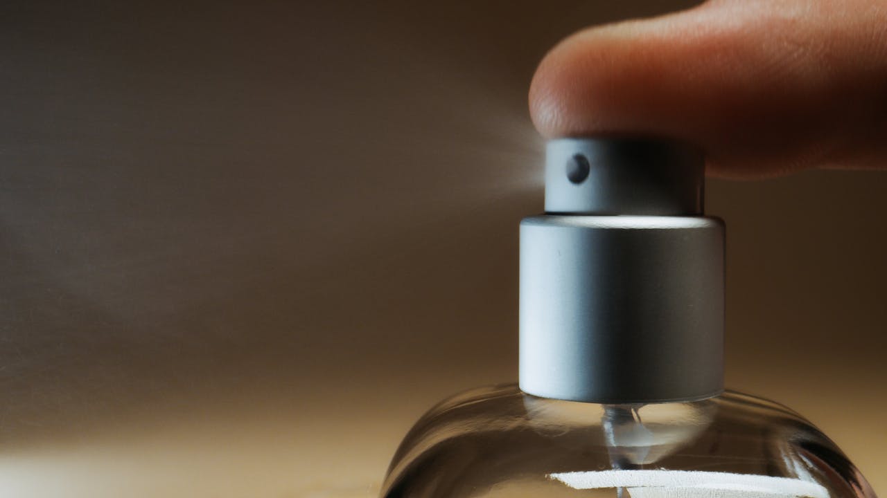 Detailed shot capturing finger pressing a perfume spray bottle, illustrating a moment of action.